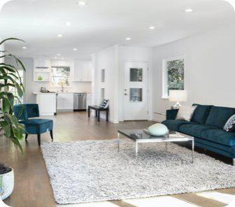 一间漂亮的全白色家庭娱乐室，中间是蓝色沙发和蓬松的地毯